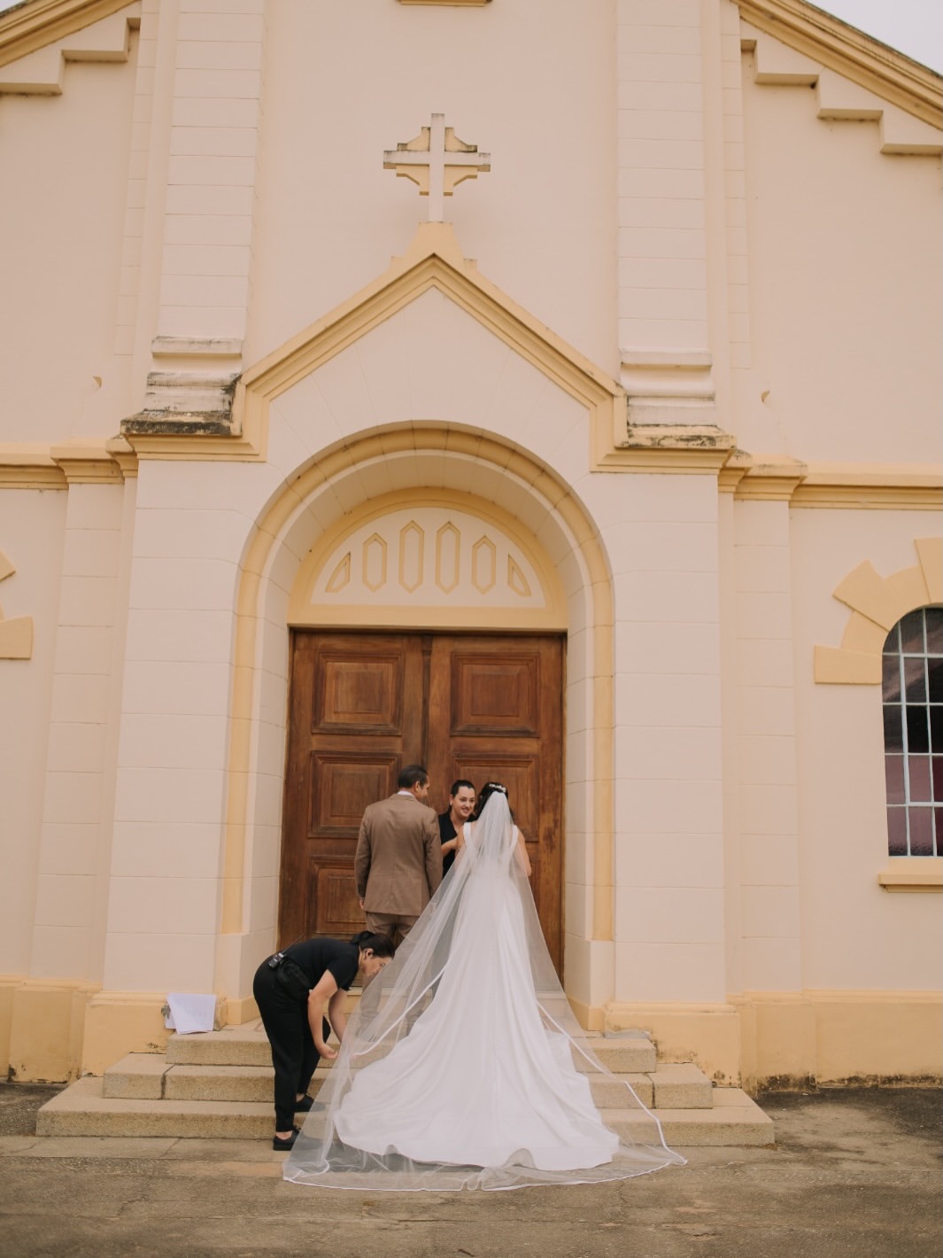 Noiva na porta da igreja com véu longo